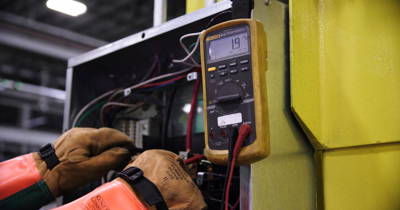About Electrician using a multimeter to fix industrial control panel wiring.