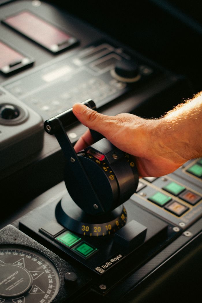A hand operating a boat's control lever, showcasing technology and precision.
